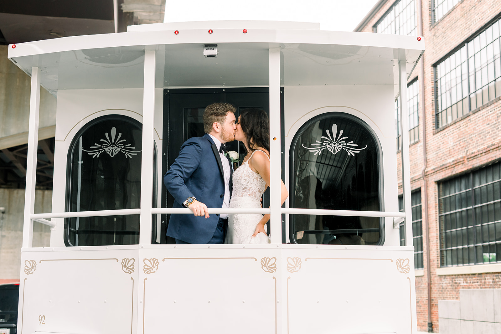 Groom and bride kiss in front of one of the Baltimore wedding venues in a white train car.