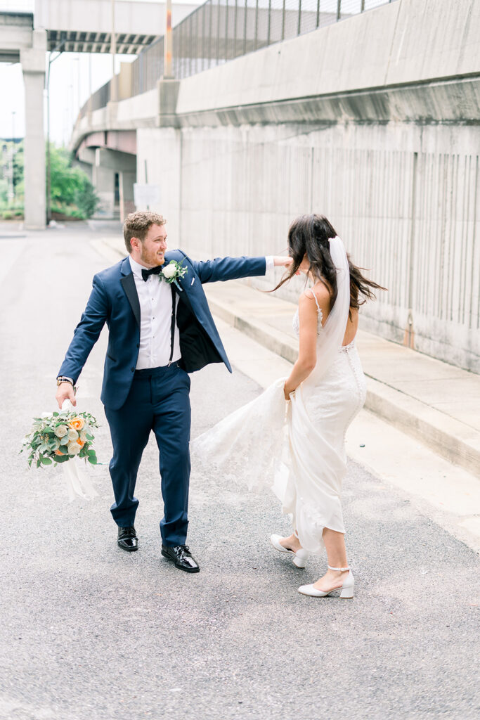 Groom spins bride in front of one of the Baltimore wedding venues. Groom holds bouquet for bride so she can hold her dress.