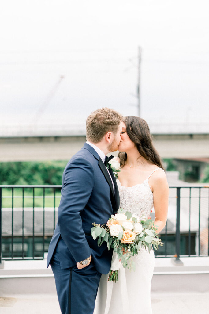 Bride and groom kiss with black metal fence behind them in front of one of the Baltimore wedding venues.
