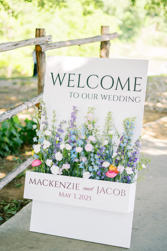Spring Austin wedding welcome sign with local wildflowers. There are mostly purple, blue, and white flowers. 