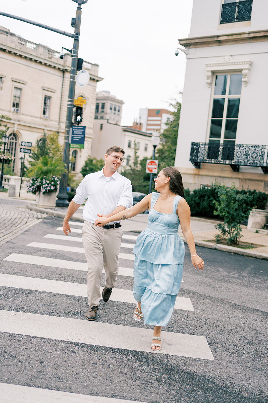 Man and woman laugh while crossing street during their Mt. Vernon engagement photos