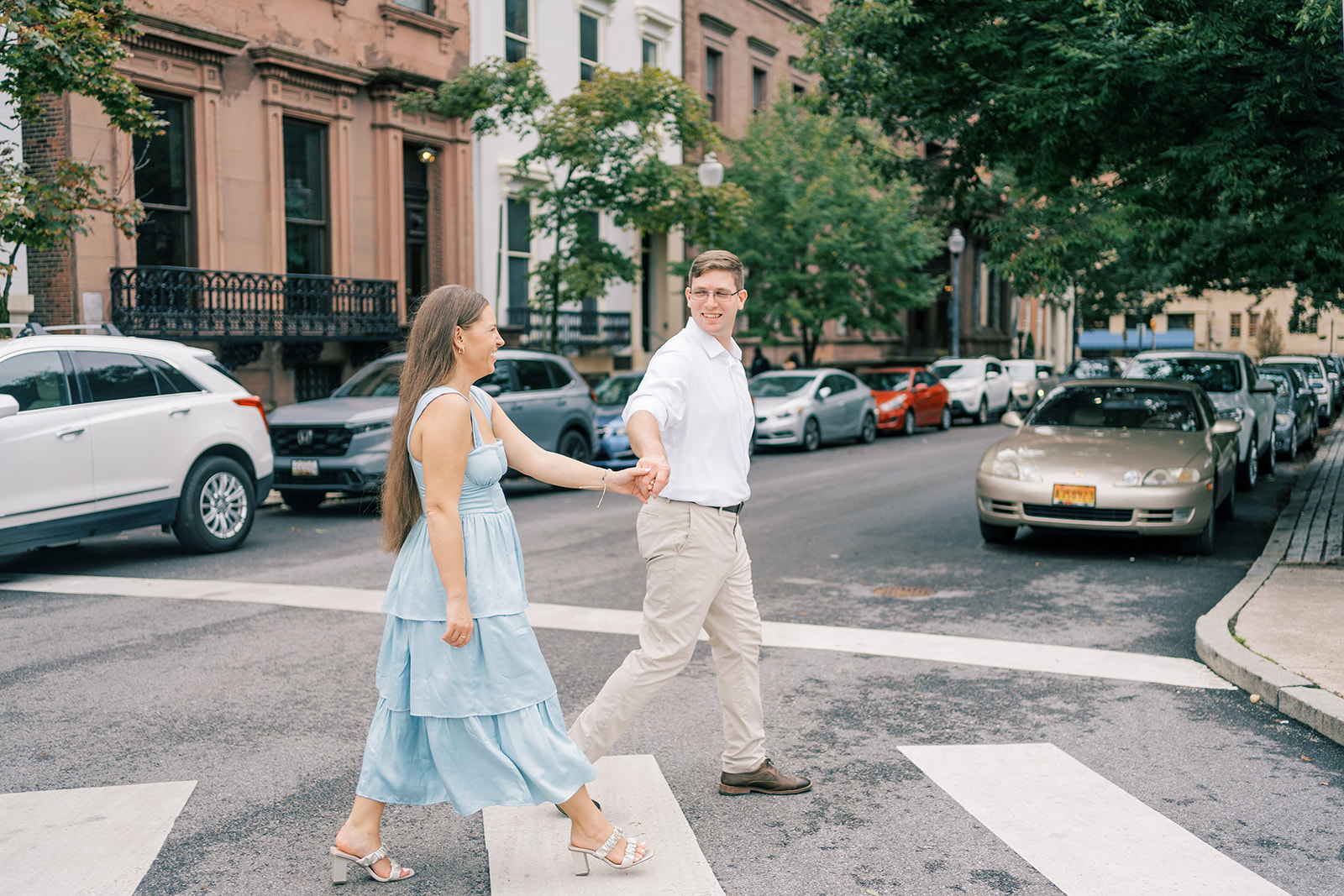 Couple holds hands while crossing street during their Mt. Vernon engagement photos